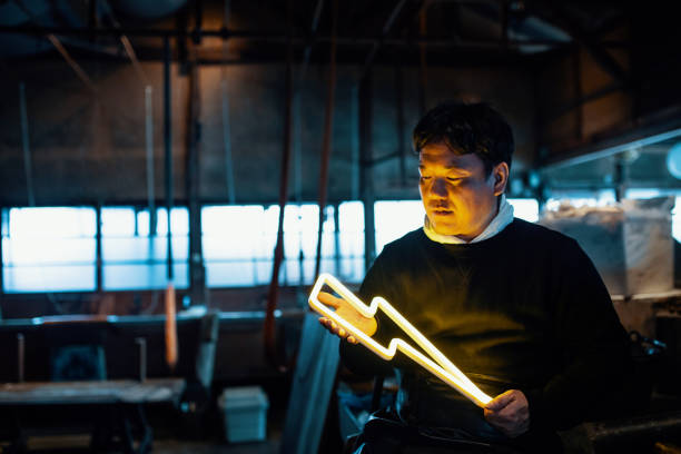 Handmade paper artist holding an illuminated lightning bolt shaped neon light