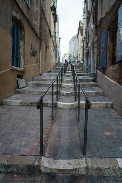 Steep and narrow pedestrian street in old town Marseille, France Marseille, France - May 18, 2018: An empty steep and narrow pedestrian street with metal railing in the middle of it in old town Marseille, France marseille panier stock pictures, royalty-free photos & images