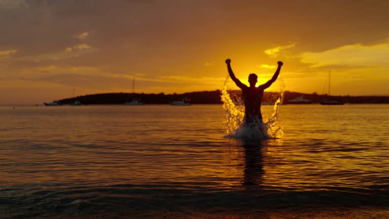 MS Silhouette exuberant man jumping out of ocean at sunset,Peljesac,Croatia