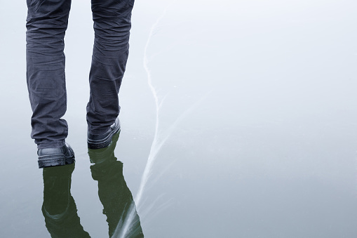 Point of view of an unrecognisable mature woman sitting at the Loch in Torridon, Scotland. She has her feet in the water, she is wearing shorts and sandals.