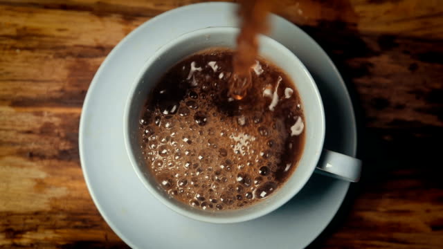 Slow motion coffee pouring in cup