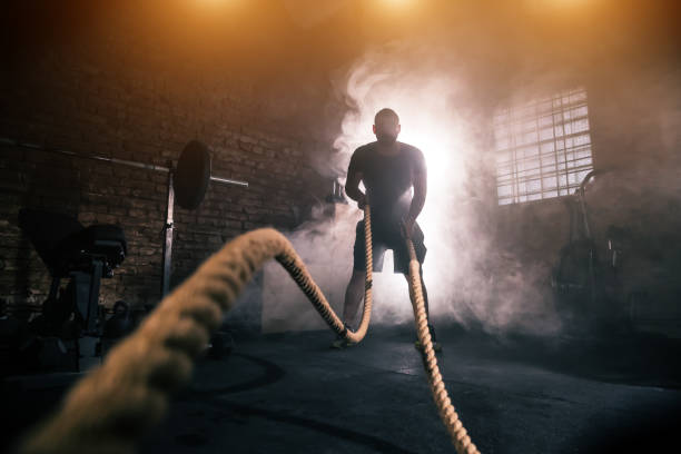 jeune homme faire le difficile exercice d’entraînement en gymnase - harsh lighting photos et images de collection