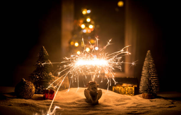 istock Glittering burning sparkler on snow with blurred Christmas tree on dark background. New Year Holiday concept with empty space for your text 1083275564