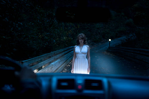Beautiful Ghostly Woman Standing on Road in Car Headlights stock photo