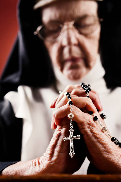 perdu dans la prière, une ancienne religieuse fermoirs un chapelet - nun catholicism praying women photos et images de collection