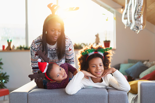 Young African - American woman enjoying Christmas day with her cute daughters.