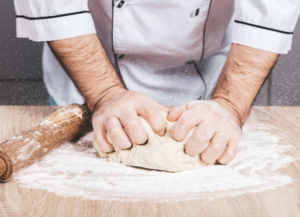 istock male cook kneads dough on the table 1083284408