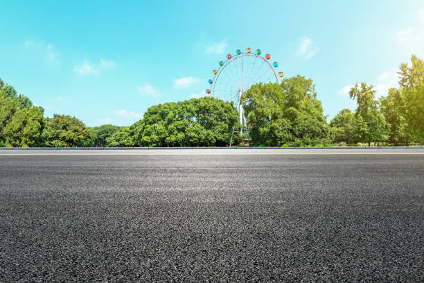 istock Asphalt road and ferris wheel with green forest landscape 1083284612