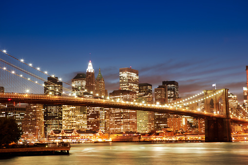 Brooklyn bridge with Manhattan buildings in background by night