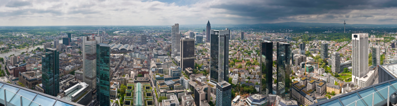 Panoramic vista across the skyscrapers, towers and landmarks of central Frankfurt's Bankenviertel financial district, from the banks of the River Main past the European Central Bank, the busy Hauptbahnhof railway station, international banks and the famous Messe exhibition complex to the green hills of Taunus, Germany. ProPhoto RGB profile for maximum color fidelity and gamut.