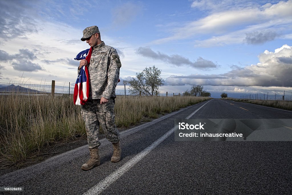 Lonely military soldier walking down a road  American Culture Stock Photo