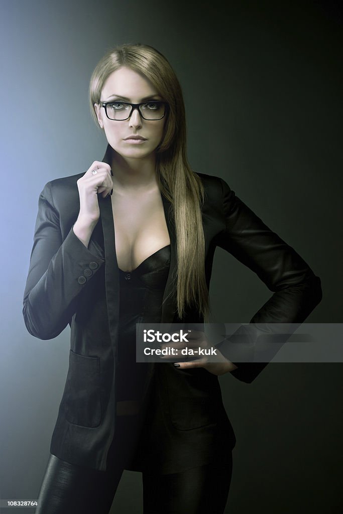 Fashion portrait of young woman Fashion portrait of young beautiful woman against dark background. Suit Stock Photo