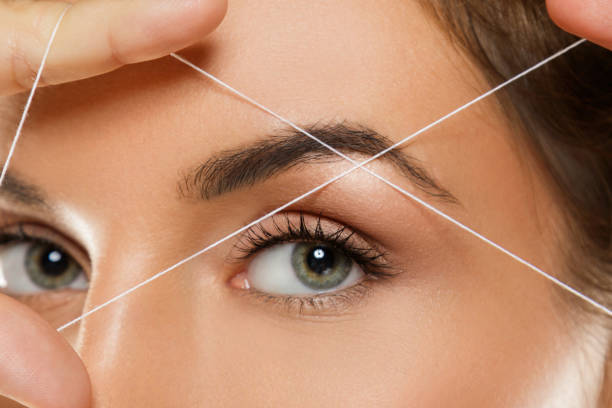 Eyebrow threading - epilation procedure for brow shape correction stock photo