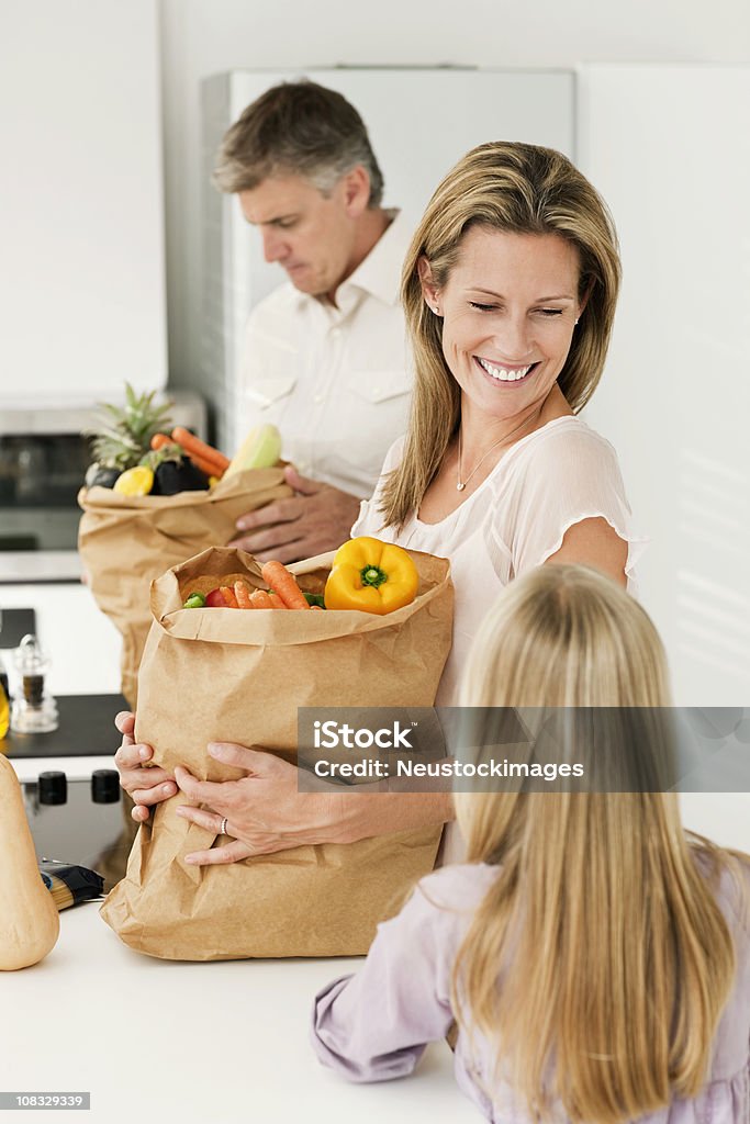 Famiglia sorridente mettendo fuori e generi di drogheria - Foto stock royalty-free di 30-34 anni