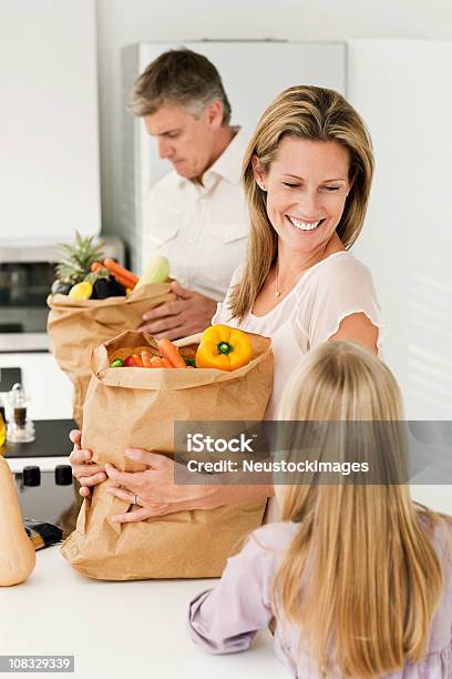 Famiglia Sorridente Mettendo Fuori E Generi Di Drogheria - Fotografie stock e altre immagini di 30-34 anni