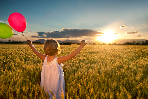 Girl in a wheat field with balloons -Slide  Motion blur on girl.