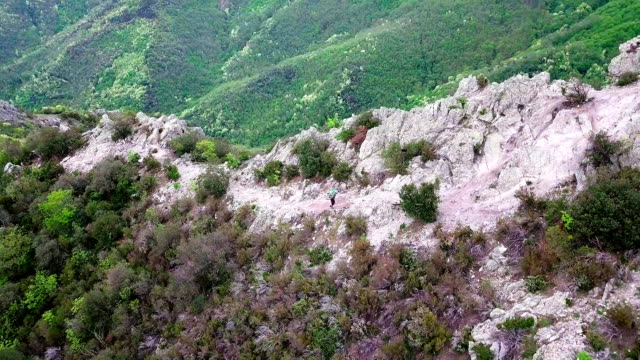 Aerial shot of a mountain biker lifting his bike on top of the mountain