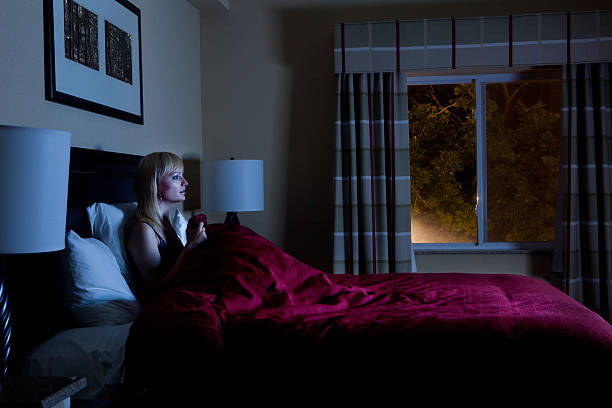 Woman in bed late at night watching TV stock photo