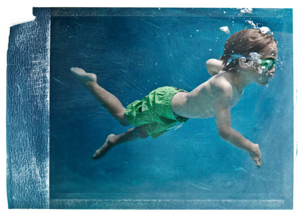 eighth years old kid swimming under the water on a pool.