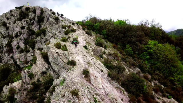Aerial shot of a mountain biker lifting his bike on top of the mountain