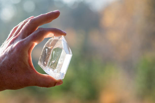 A Hand holding a transparent crystal quartz gemstone
