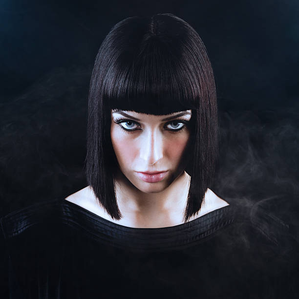 Beautiful Woman with Blunt Dark Hair and Smoky Black Background stock photo