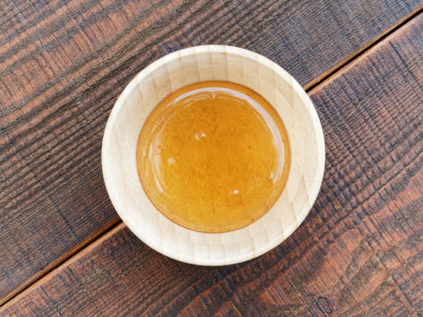 Fresh honey in wooden honey bowl on wooden table, top view. stock photo