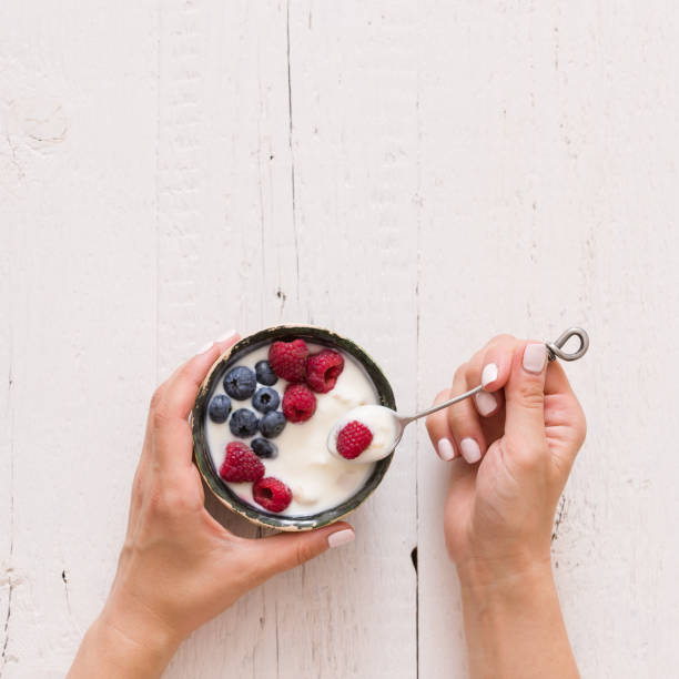 widok z góry na ręce dziewczyny trzymając miskę z organicznym jogurtem waniliowym ze świeżymi jagodami. zdrowe odżywianie. - blueberry food fruit berry fruit zdjęcia i obrazy z banku zdjęć