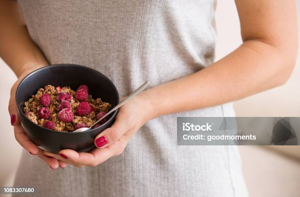 Photo libre de droit de Gros Plan Des Mains Dune Jeune Femme Tenant Un Bol Noir Avec Granola Organique Avec Lait De Coco Et Framboises Mode De Vie Sain banque d'images et plus d'images libres de droit de Adulte