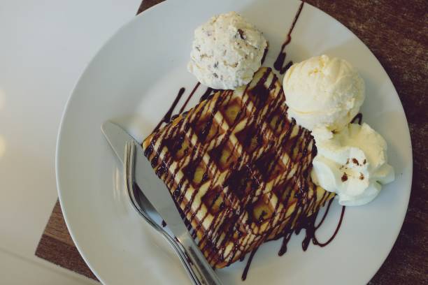 istock Waffle and vanilla ice cream in white plate on wooden table 1083309438