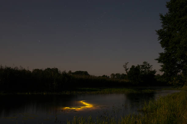 istock Underwater diving at night with flashlight. Light from river bottom. Full moon over foggy river Stochid in Volyn. Moon light at night landscape 1083311998