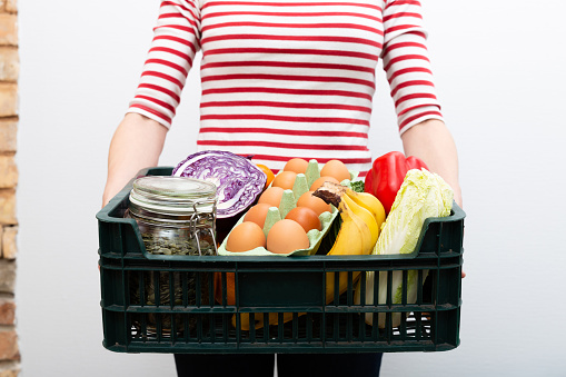 Woman holding box of grocery food and from store. Online grocery shopping service concept