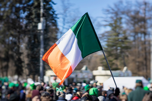 Bandera de primer plano de Irlanda en manos sobre fondo de cielo azul durante la celebración del día de San Patricio photo