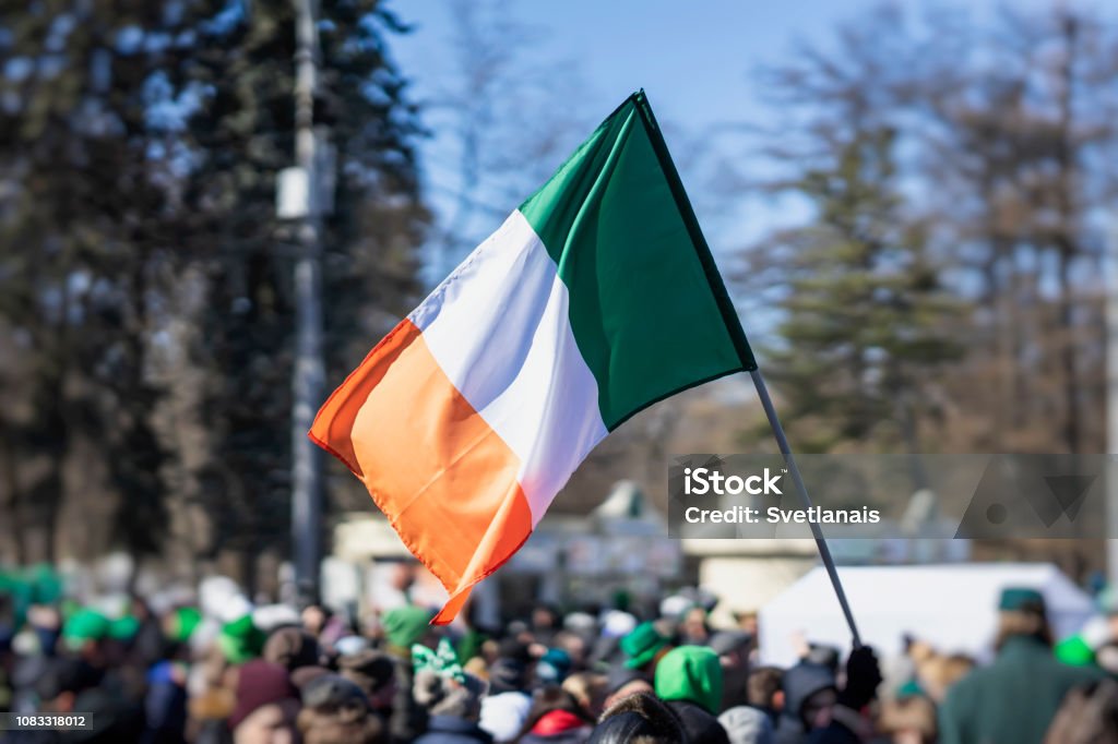 Flag of Ireland close-up in hands on background of blue sky during the celebration of St. Patrick's Day Flag of Ireland close-up in hands on background of blue sky during the celebration of St. Patrick's Day in the city St. Patrick's Day Stock Photo