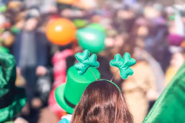 Photo of Clover head decoration on head of girl close-up. Saint Patrick day, parade in the city, selectriv focus