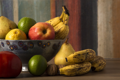 Bowl of different fruits on a colorful background