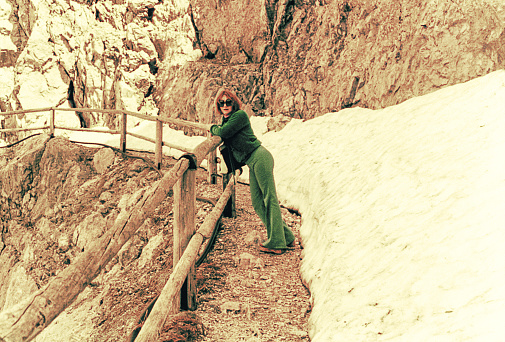 vintage photo of a woman on snowy scenery leaning on a balcony.