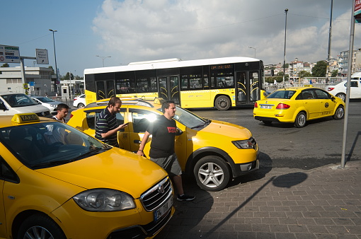 Istanbul, Turkey - September, 2018: Three young men crossing road near yellow taxi cars on the street in Istanbul. Mostly bright yellow color picture.