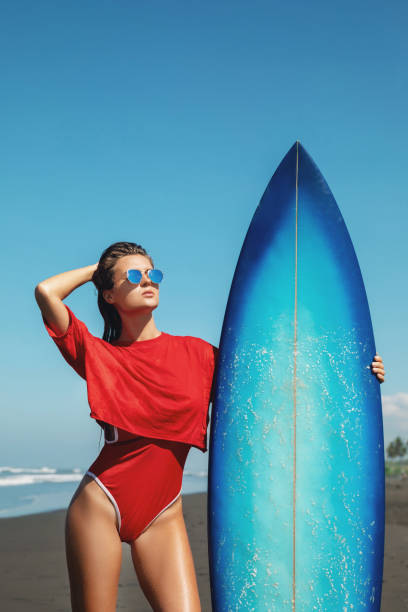 istock Beautiful woman surfer with shortboard on the beach 1083354106