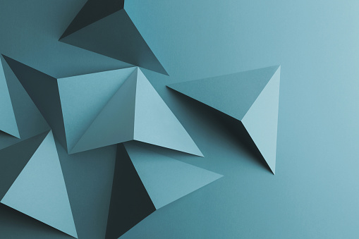 Composition with light blue papers folded in geometric shapes, texture background