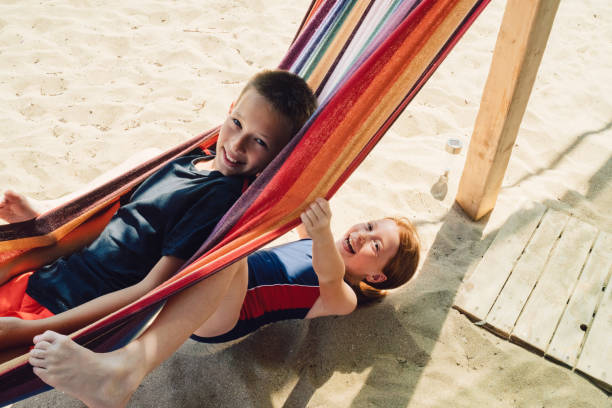 Friends on beach holiday swinging in hammock