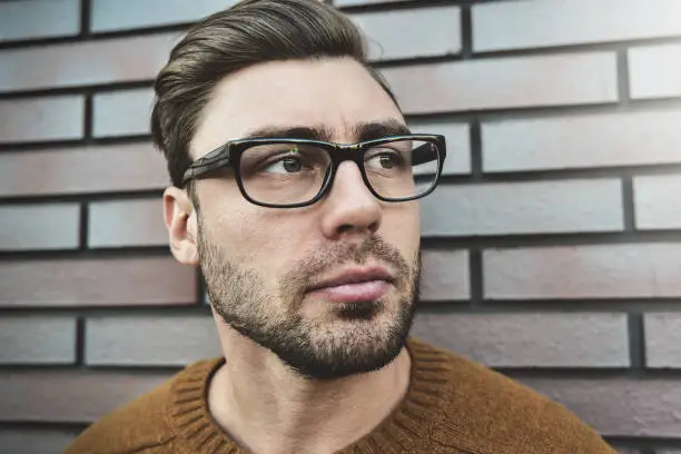 Photo of Portrait of a caucasian handsome man in eyeglasses that is seriously frowning. Emotional face concept.