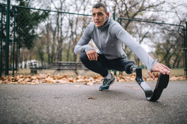 Motivated amputee athlete stretching before running Young and athletic man with a artificial leg, exercising outdoors, living a healthy lifestyle recovering. athlete with disabilities photos stock pictures, royalty-free photos & images