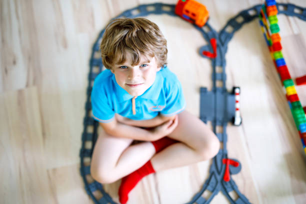 istock Adorable little blond kid boy playing with colorful plastic blocks and creating train station. Child having fun with building railway toys at home.. 1083386164