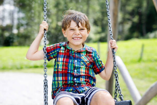 istock Funny kid boy having fun with chain swing on outdoor playground while being wet splashed with water. child swinging on summer day. Active leisure with kids. Happy crying boy with rain drops on face. 1083388500