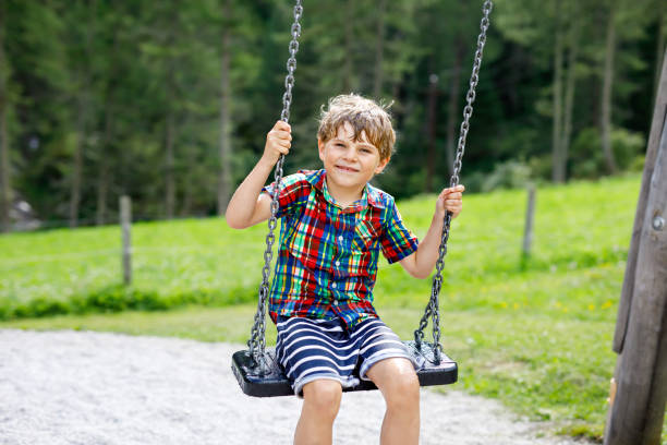 istock Funny kid boy having fun with chain swing on outdoor playground while being wet splashed with water. child swinging on summer day. Active leisure with kids. Happy crying boy with rain drops on face. 1083388582