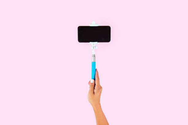 istock Selfie stick and white smart phone on pink background 1083391170