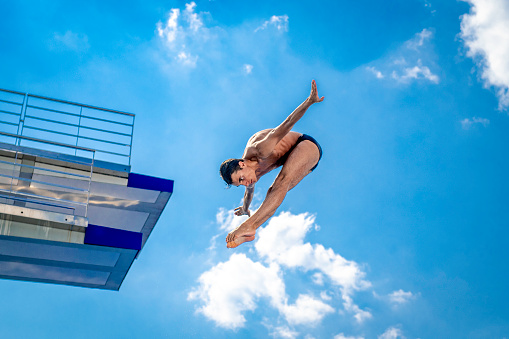 Mid-air shot of  springboard diver jumping into the pool, copy space.