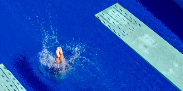 Platform diving Splash of a springboard diver on a surface of a swimming pool, copy space. diving into water stock pictures, royalty-free photos & images
