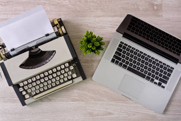 Old typewriter with paper sheet and laptop side by side. stock photo